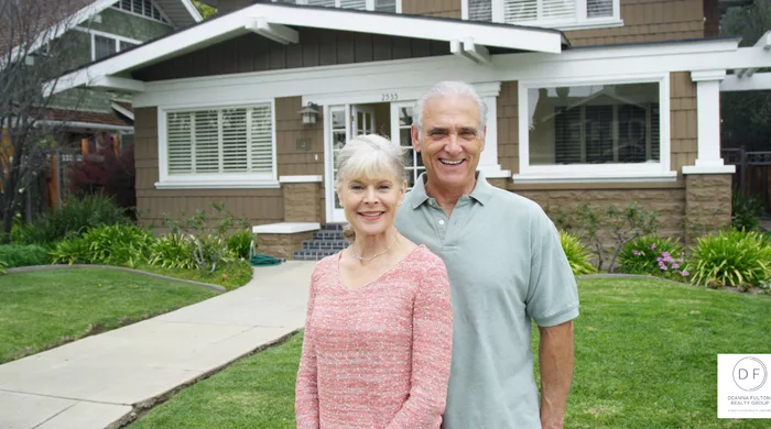 Happy older couple in front of house