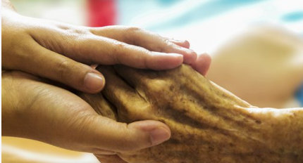 Two young hands holding an elderly persons hand for support